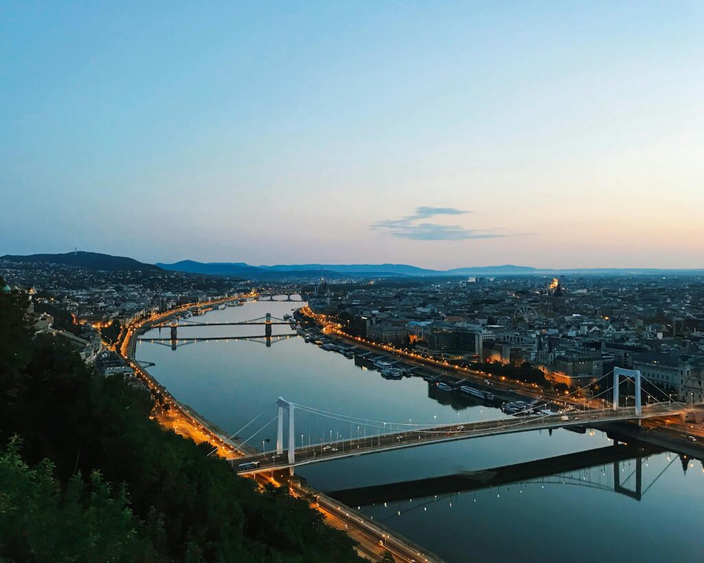 Stunning aerial view of Budapest focusing on the brightly lit Elisabeth Bridge at twilight, showcasing the city's beauty.